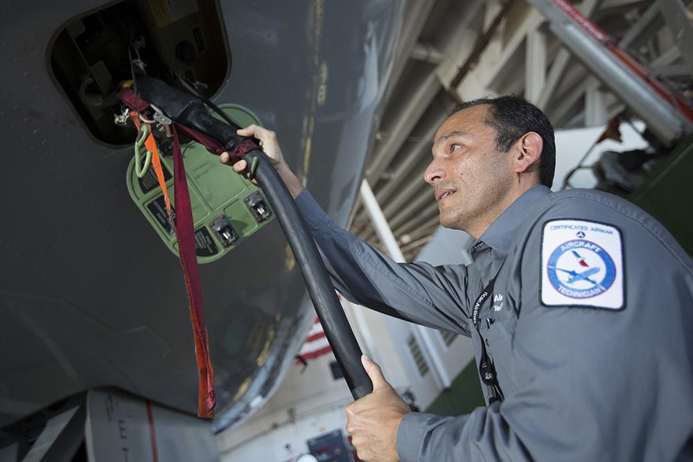 Aircraft technician connecting hose to aircraft